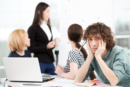 Sad creative businessman looking at camera with his business team on background. Office interior with window. Concept for teamworkの写真素材