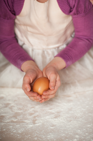 Close up photo of egg in little hands. Concept for cooking in the kitchenの写真素材