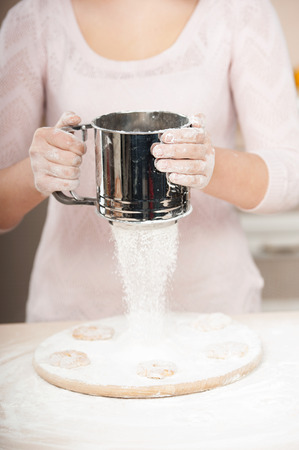 Close up photo of flour and sieve in female hands. Concept for cooking in the kitchenの写真素材