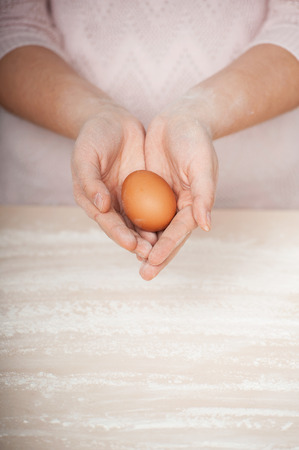 Close up photo of egg in female hands. Concept for cooking in the kitchenの写真素材