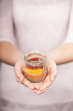 Close up photo of colored salt in glass jar in female hands. Concept for cooking in the kitchenの写真素材
