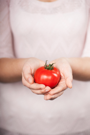 Close up photo of tomato in female hands. Concept for cooking in the kitchenの写真素材