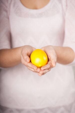 Close up photo of lemon in female hands. Concept for cooking in the kitchenの写真素材