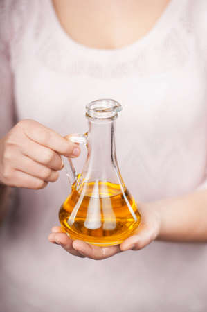 Close up photo of female hands holding jug of oil. Concept for cooking in the kitchenの写真素材