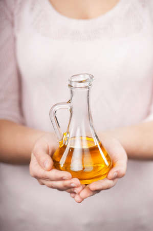 Close up photo of jug of oil in female hands. Concept for cooking in the kitchenの写真素材