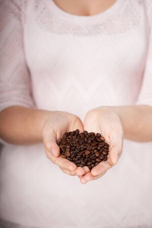 Close up vertical photo of coffee grains in female hands. Concept for cooking in the kitchenの写真素材