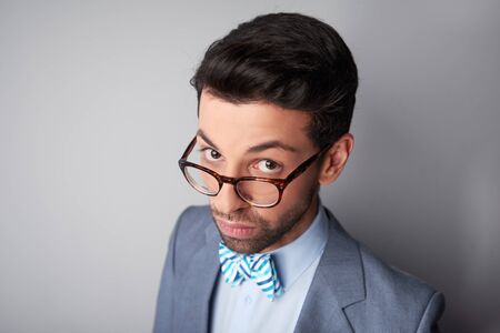 Portrait of elegant casual young man with glasses wearing jacket and bow tie. Man looking steadily and intently at cameraの写真素材
