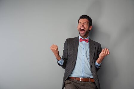 Portrait of positive casual young man wearing tweed jacket and red bow tie. Very happy man showing successの写真素材