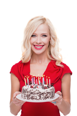 Photo of young beautiful smiling blonde woman. Woman holding cake with candles and standing on white background. Concept for happy birthdayの写真素材