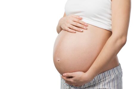 Close up photo of young pregnant woman belly. Isolated on white background. Concept for pregnancyの写真素材