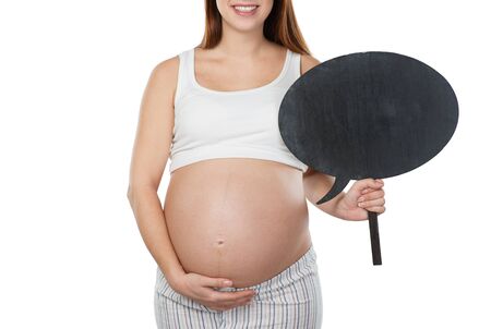 Close up photo of young pregnant woman. Woman holding dialog cloud near her belly. Isolated on white background. Concept for pregnancyの写真素材