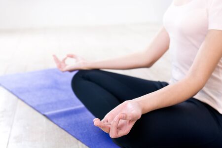 Close up photo of woman hands. Woman meditating while doing lotus pose and sitting on violet fitness matの写真素材