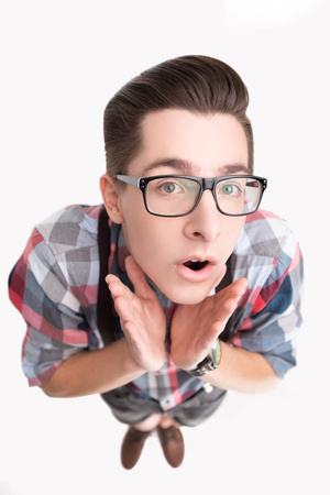Curious young nerd in glasses and checkered shirt isolated on white backgroundの写真素材