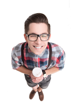 Young nerd in glasses and checkered shirt with coffee cup isolated on white backgroundの写真素材