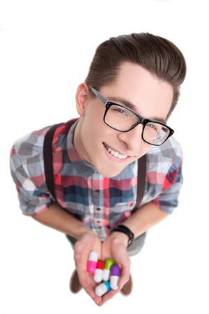 Young nerd in glasses and checkered shirt with pills isolated on white backgroundの写真素材