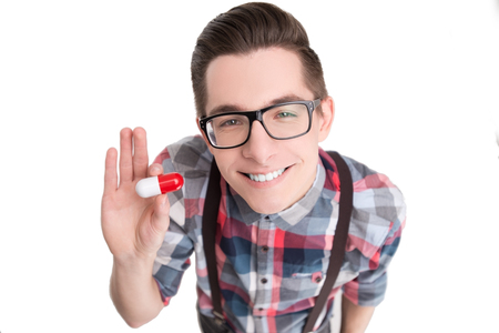 Young nerd in glasses and checkered shirt with pill isolated on white backgroundの写真素材
