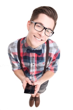 Young nerd in glasses and checkered shirt with smartphone isolated on white backgroundの写真素材