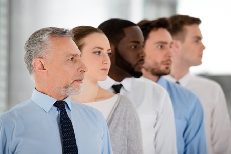 Multi-ethnic business team standing in a row and looking forward purposefullyの写真素材