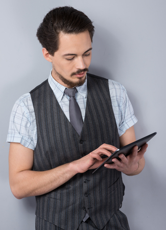 Photo of stylish young businessman wearing striped suit. He using tablet computerの写真素材