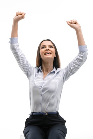 Photo of young successful businesswoman wearing suit. She smiling and holding arms up. Isolated on white backgroundの写真素材