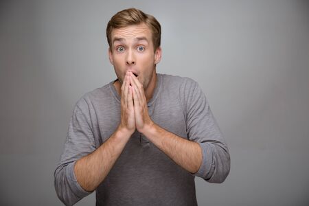 Portrait of handsome stylish young man on grey background. Man looking at camera amazedlyの写真素材