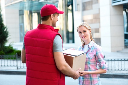 Colorful picture of courier delivers package for woman. Woman accepts the parcel and smiling.