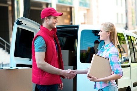 Colorful picture of courier delivers package for woman. They are shaking hands.の写真素材