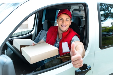 Colorful picture of courier delivers package. Man is riding in the car, holding the box and smiling.の写真素材