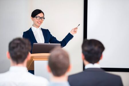 Photo of beautiful young business woman making presentation with whiteboard on seminar or meeting to business peopleの写真素材