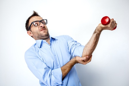 Funny photo of businessman with beard wearing shirt and glasses. Stressful businessman trying to exercise with small dumbbell. Isolated on white backgroundの写真素材