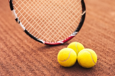 Close up photo of three tennis balls and racquet on tennis courtの写真素材