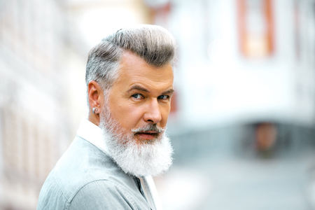 Portrait of stylish handsome adult man with beard standing outdoors. Man looking at cameraの写真素材