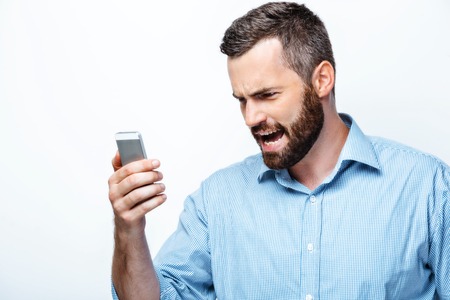 Young businessman with beard on white background screaming at mobile phoneの写真素材