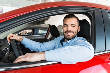 Photo of young man sitting inside new car and smiling. Concept for car rentalの写真素材