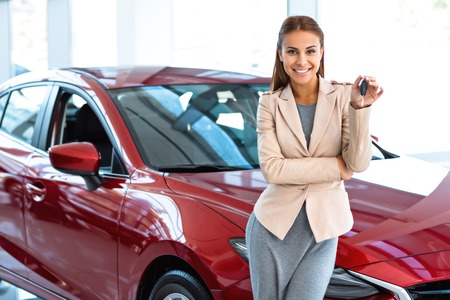 Photo of happy young mixed race woman showing key to her new car. Concept for car rentalの写真素材
