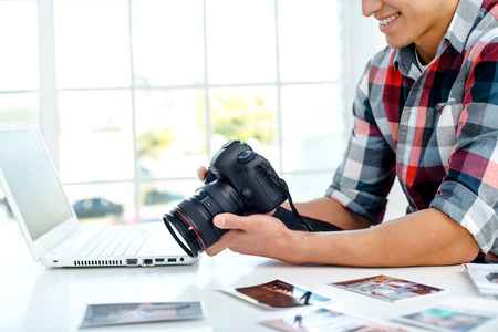 Professional photographer with camera and laptop computer working in officeの写真素材