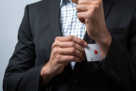Studio shot of young man's hand on grey background. Man wearing jacket and shirt. Man holding card in sleeveの写真素材