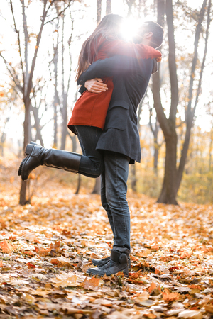 Romantic photo of cute couple outdoors in fall. Young man and woman standing with blanket. Light flare between themの写真素材