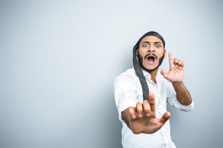 Fun picture of young mixed race man with beard standing on grey background. Young man with tie on headの写真素材