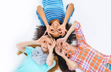 Top view portrait of beautiful three mixed-race girls on white background. Teenagers smiling and looking at cameraの写真素材