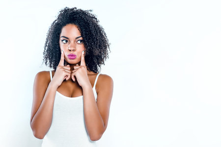 Bright picture of beautiful young mixed race woman with curly hair on white background. Girl inflating cheeksの写真素材