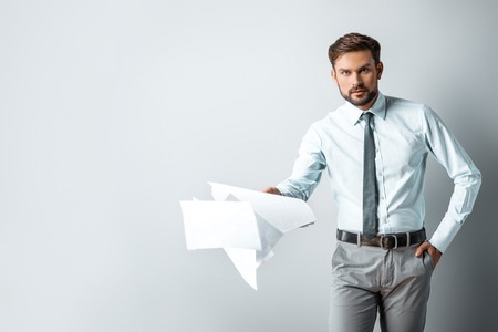 Studio shot of young attractive businessman. Businessman seriously looking at camera and holding crumpled blank paperの写真素材
