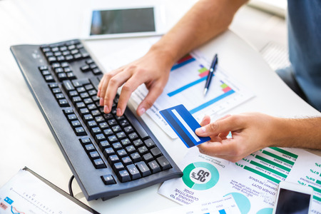 Close up photo of young businessman. Young businessman working with computer and holding credit card. Focus on keyboardの写真素材