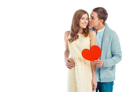 Romantic photo of beautiful couple on white background. Handsome young man giving Valentine card to his girlfriend and kissing herの写真素材