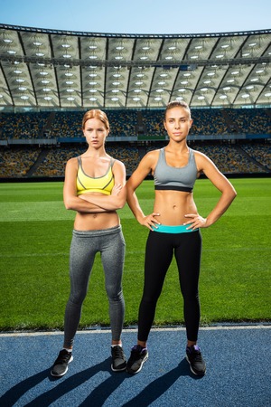 Young sporty women standing on racetrack. Fit well formed women are at large nice modern stadiumの写真素材