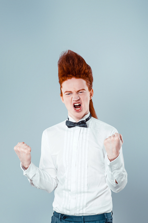 Stylish redheaded young man with bouffant on head. Boy wearing shirt with bow-tie and showing successの写真素材
