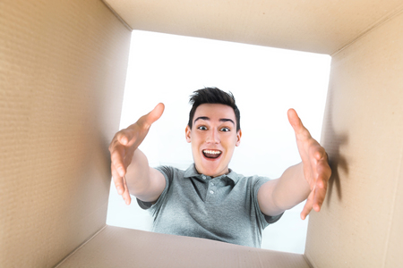 Man smiling, unpacking and opening carton box, and looking insideの写真素材