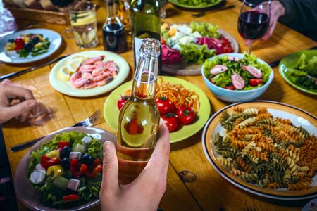 Close up creative photo of delicious meal on wooden vintage table. Focus on male hand with beerの写真素材