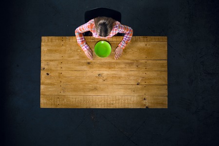 Top view creative photo of girl sitting at wooden vintage table. Girl with empty green plateの写真素材
