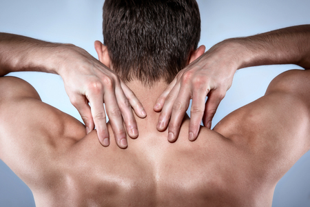 Studio shot of handsome young man with naked torso. Man suffering from neck acheの写真素材